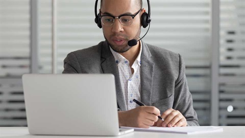 a man with a headset looking at his laptop