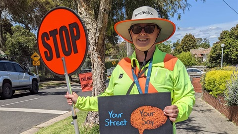 School crossing supervisor holding a Your Street Your Say sign