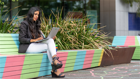 Lady using laptop on Darebin park bench.png