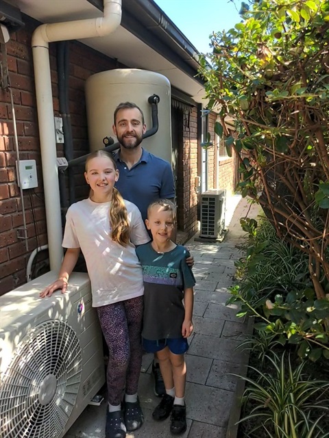 Family standing in front of electric hot water system