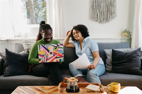 A person on her laptop with another person looking over