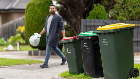 Man taking bag of waste to his bin