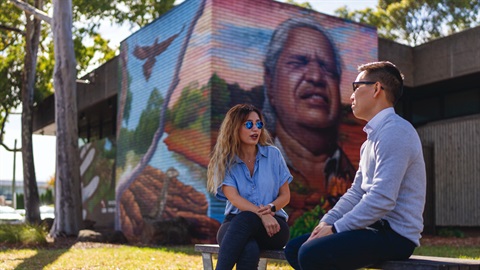 People sitting outside the library with a mural in the background.jpg