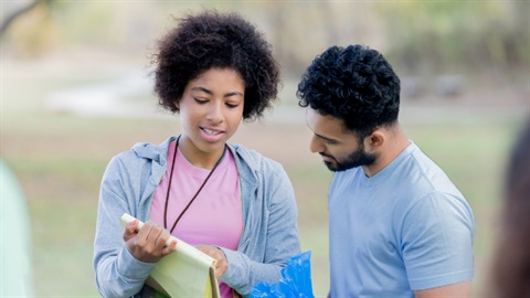 Two volunteers looking at a notepad