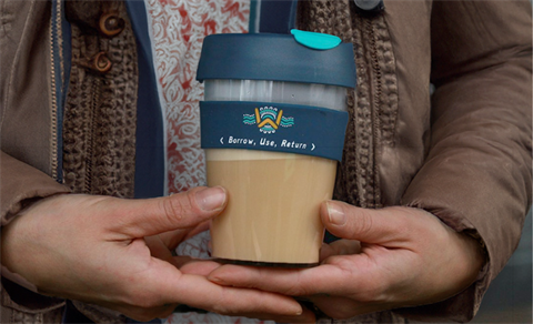 Two hands holding a reusable coffee cup.