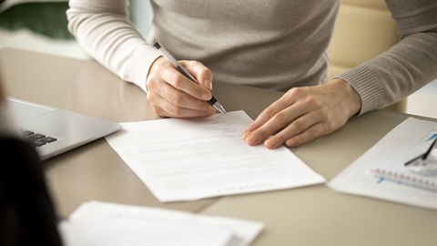 Hand holding pen, putting signature at official paper