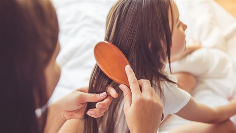 An adult brushing a child's hair