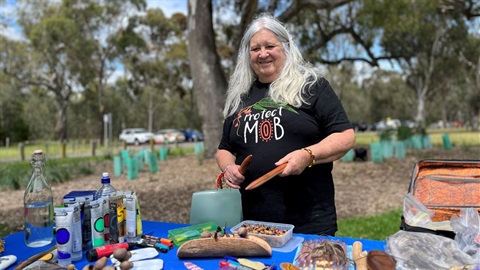 Older First Nations woman with long grey hair and wearing a black t-shirt.