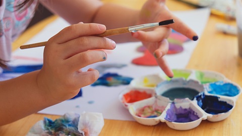 Paint brushes and paint palette with young child