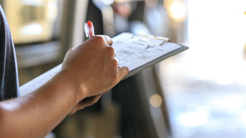 Person writing on clipboard