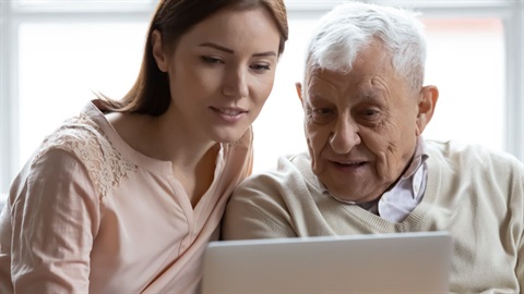 young women helping older man with laptop