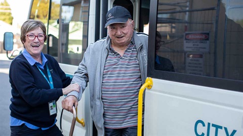older man being helped off bus