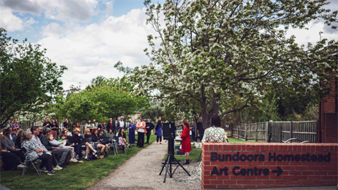A group of people gather in front of Bundoora Homestead