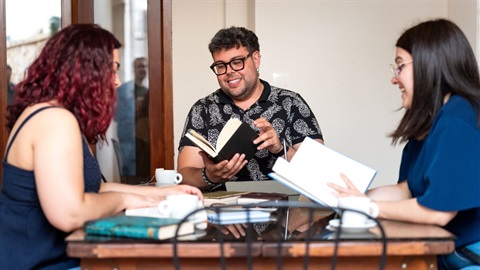 Three young people sitting at a table reading books