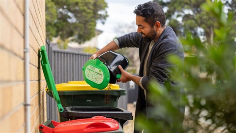 Man putting green waste into green bin for collection