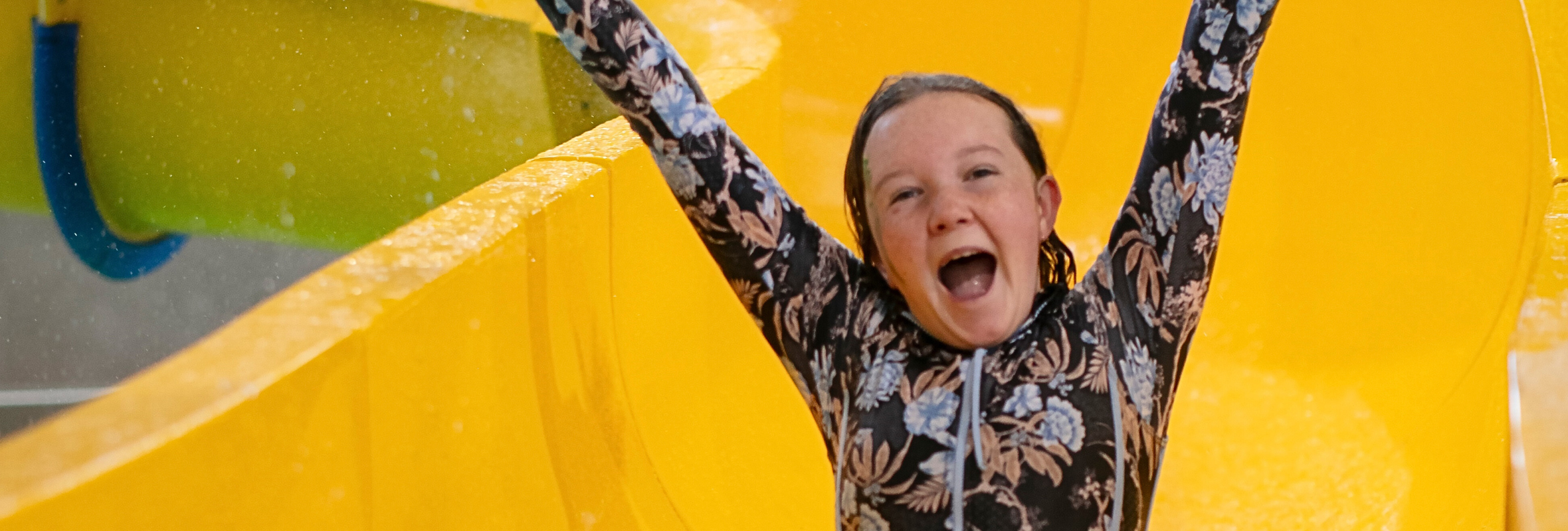 Young girl going down a water slide with her arms outstretched 