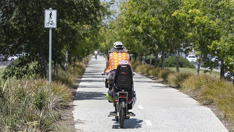 Cyclist with child riding along a bike path on a sunny day