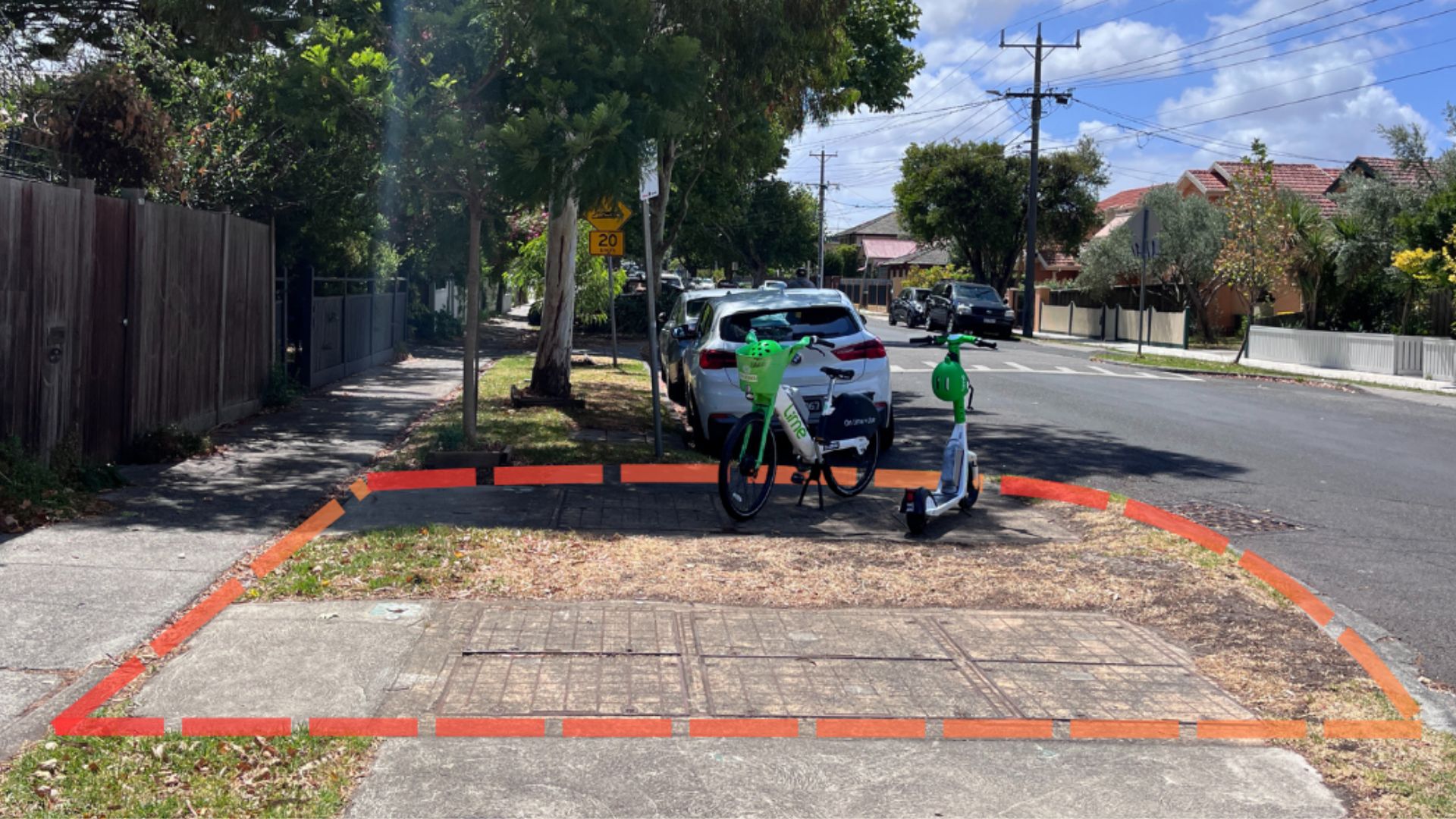 Two white e-bikes with green baskets parked on a kerb outstand