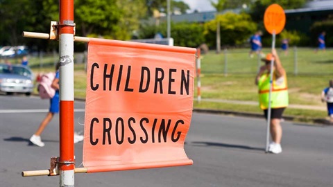 Road safety closeup of children crossing sign with crosswalk in background