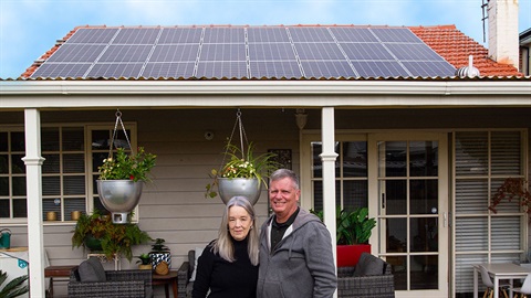Couple in front their house with solar panels on the roof