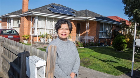 Darebin resident standing outside her house with installed solar panels