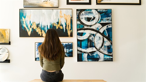 A seated person considering a wall of art