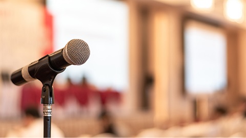 Microphone on stand in foreground blurred background of large windowed room