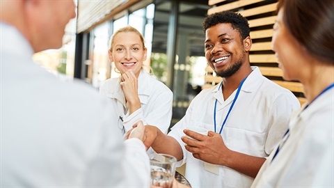 four people around a table talking and shaking hands